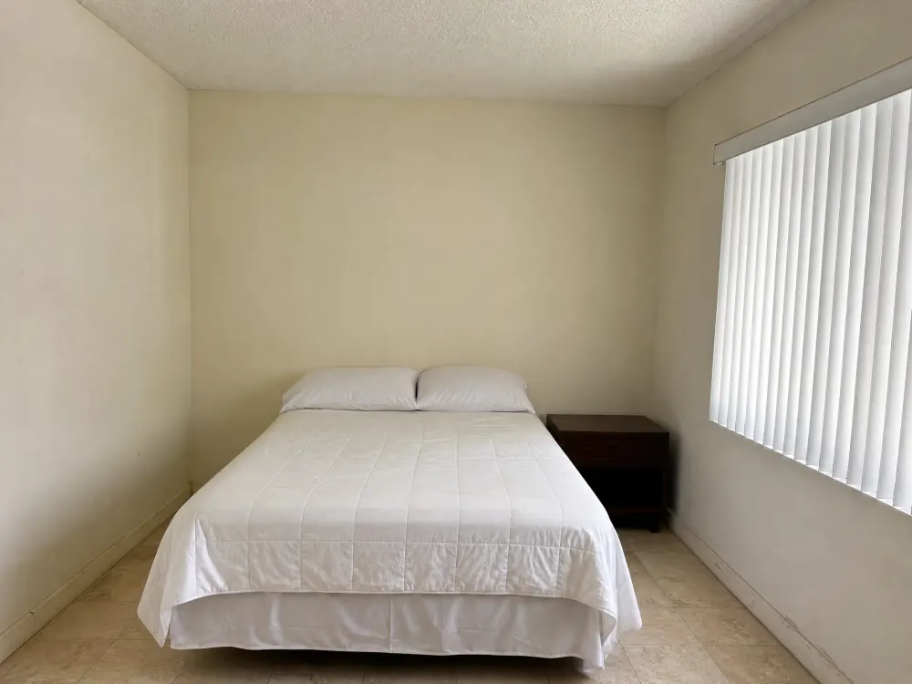 Bedroom with plain off-white walls before the headboard wall was papered