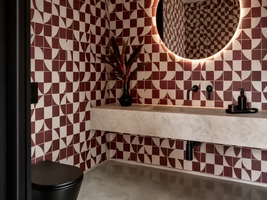 Oxblood and cream geometric wallpaper in a powder room with matte black fixtures