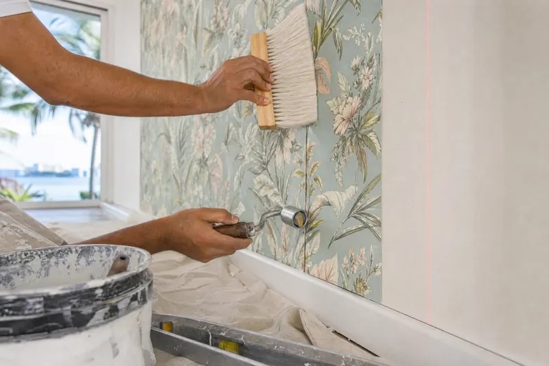 Installer smoothing a wallpaper panel with a brush, working a seam by hand